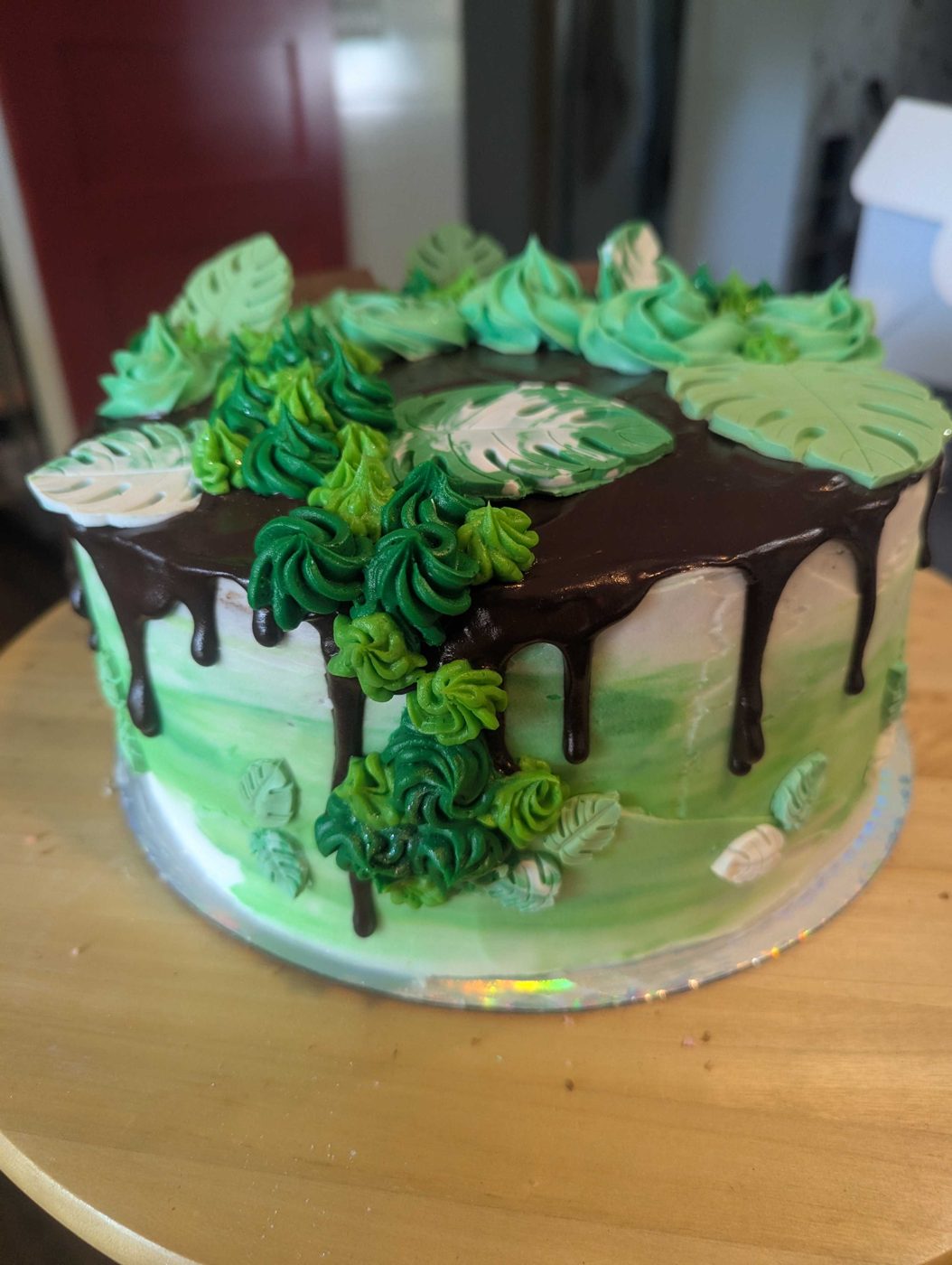 Green ombre cake with chocolate drip, piped succulents, and monstera leaves